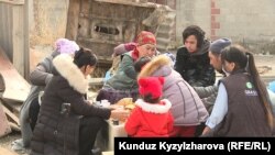 Марал Шаболотова балдары менен бузулган үйүнүн короосунда отурат. Сүрөт 3-мартта тартылган. 