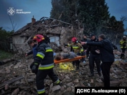 Рятувальники виносять людину, яку знайшли під завалами, зруйнованого російським ударом приватного будинку у селі Лапіївка, Львівщина. Світанок 5 жовтня 2025 року