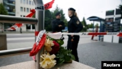 Қарулы шабуылдан адамдар қаза тапқан жердегі гүлдер мен полиция қызметкерлері. Мюнхен, 23 шілде 2016 жыл.