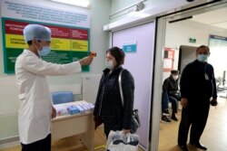 Медицина қызметкері ауруханаға келген адамдардың дене қызуын өлшеп жатыр. Алматы, наурыз айы 2020 жыл.