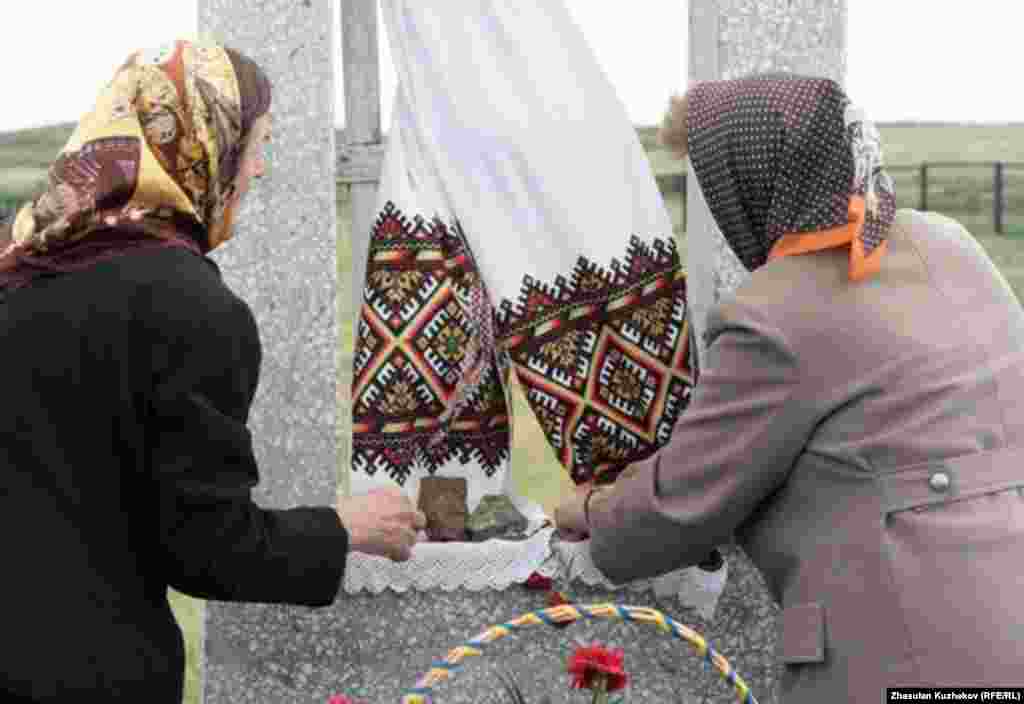Караганды облусундагы Спасск көрүстөнүндө жаткан украин туткундарына арналган эстелик жазууга аялдар гүлчамбар коюуда. 31.5.2011.