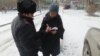 Полиция қызметкері Азаттық тілшісі Сәния Тойкенге тергеуге куәгер ретінде шақыртылатыны туралы қағаз тапсырып тұр. Ақтау, 17 ақпан 2017 жыл.