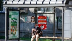 Мужчина сидит на автобусной остановке в Алматы.